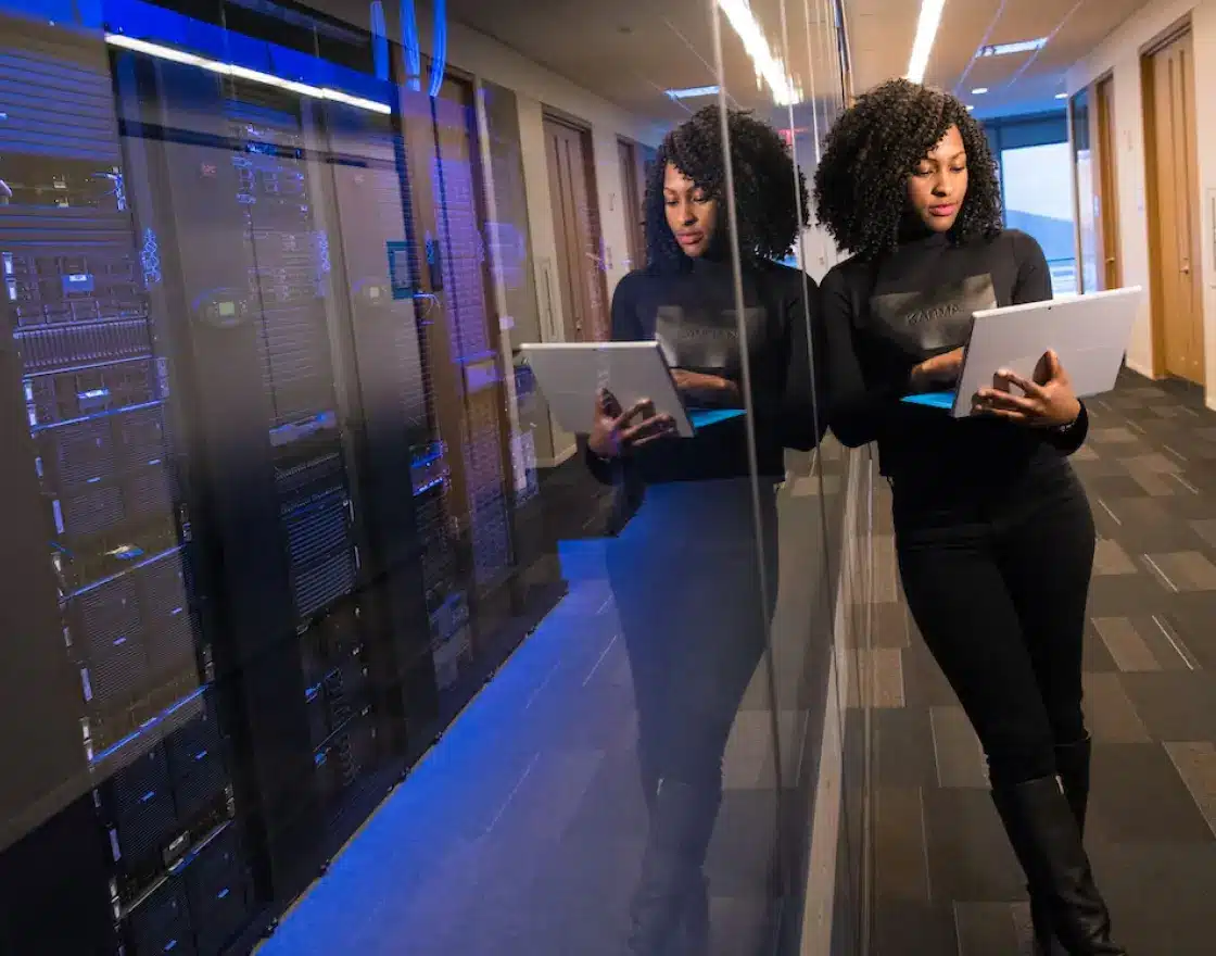 Woman with computer leaning against IT room
